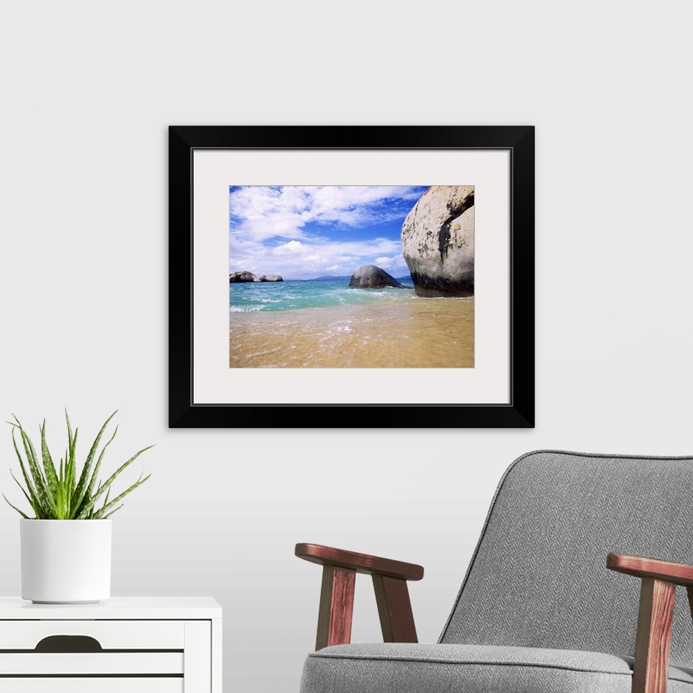 A modern room featuring This landscape photograph taken at ground level shows waves rocking against the sandy shore and l...