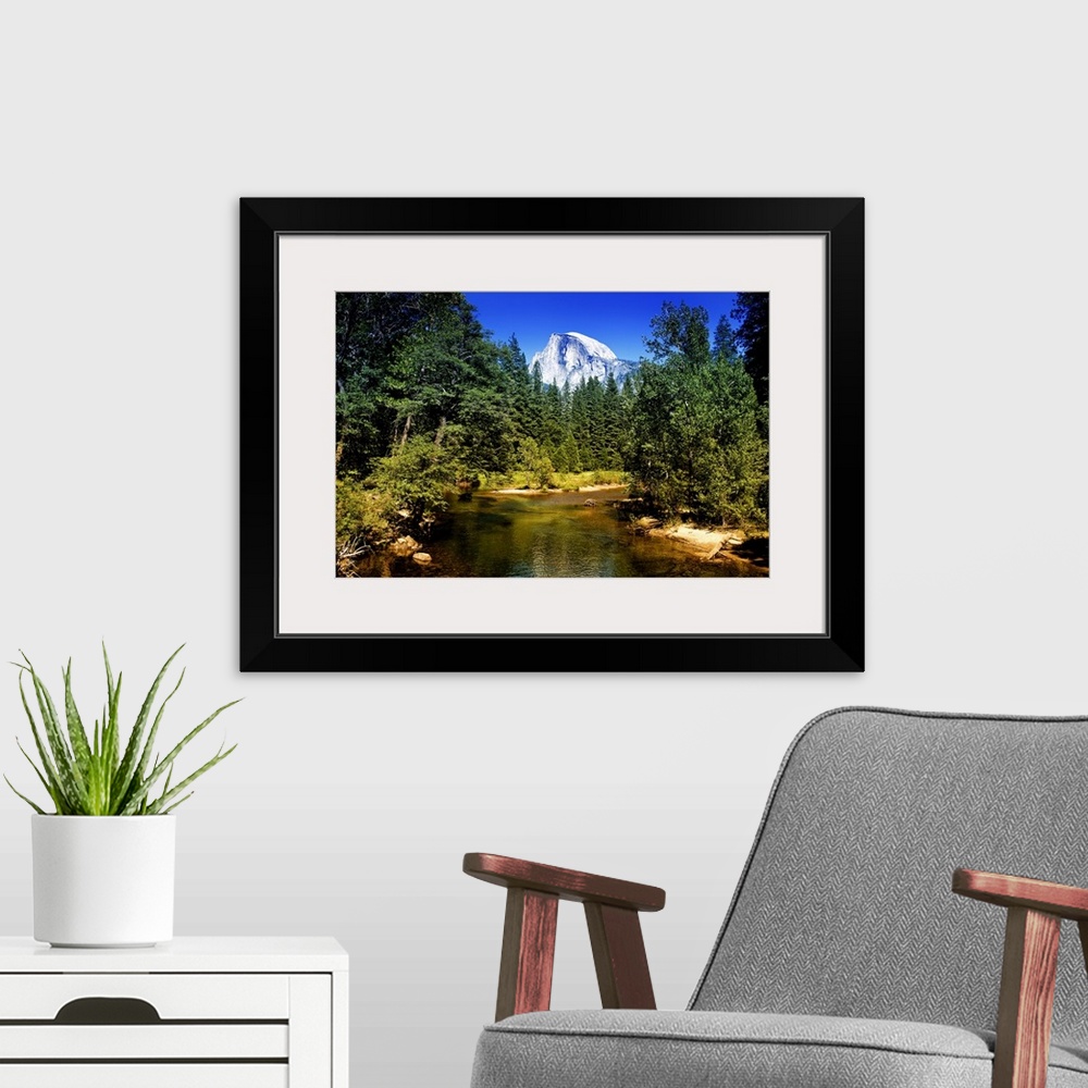 A modern room featuring The peak of Half Dome can be seen over the tops of pine trees in California's Yosemite National P...