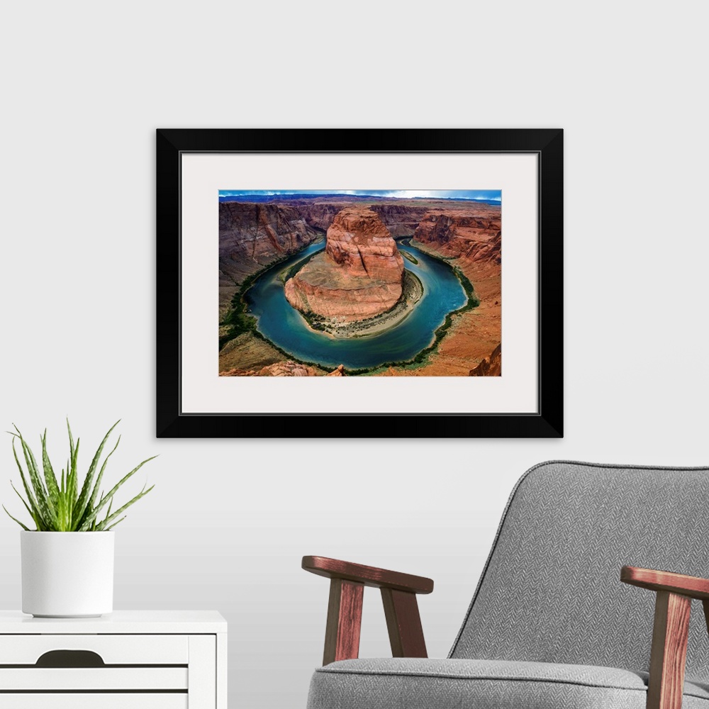 A modern room featuring Horseshoe Bend section of the Colorado River with partly cloudy skies and rain in the distance.
