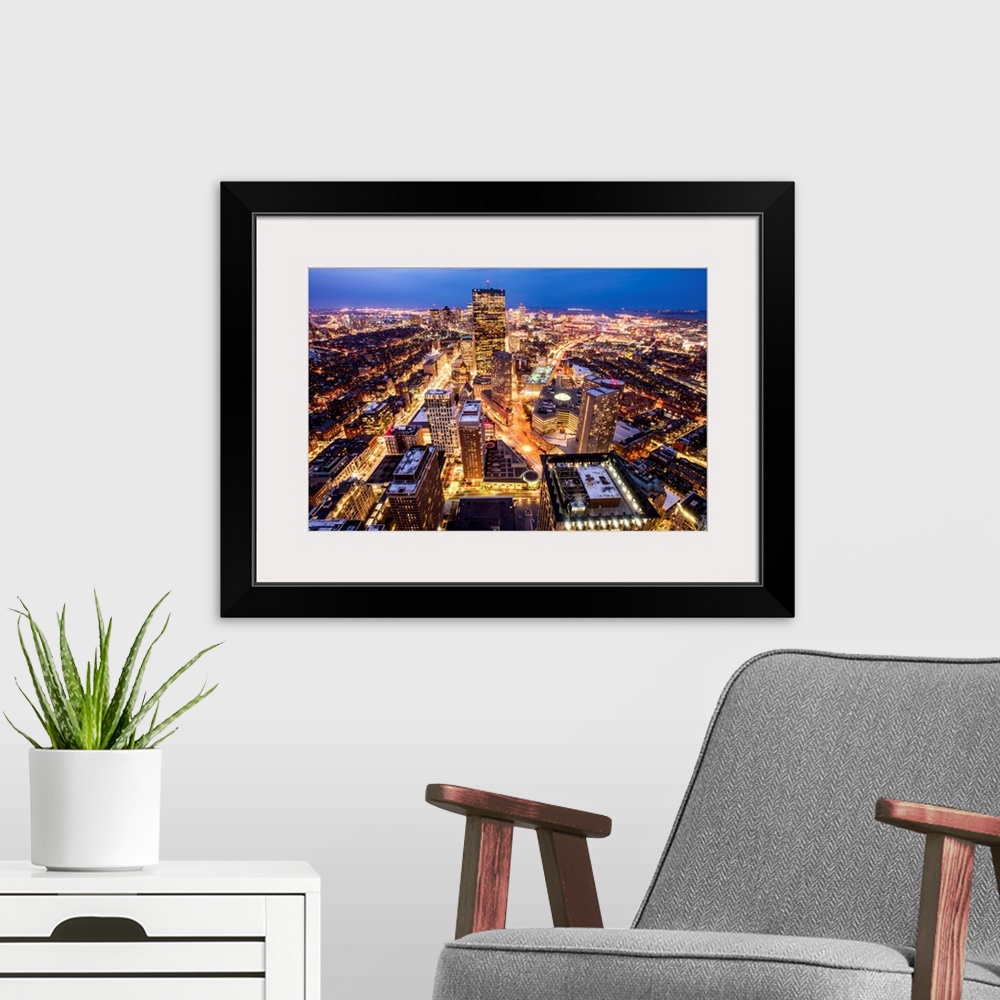 A modern room featuring Aerial view of the city of Boston, Massachusetts, lit up at night.