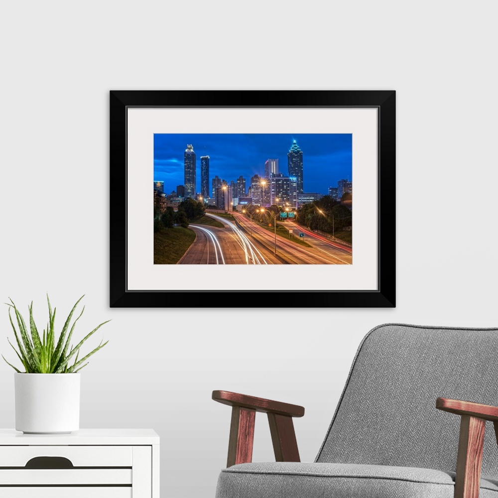 A modern room featuring Bright light trails from traffic on the freeway, headed towards the Atlanta, Georgia skyline at t...