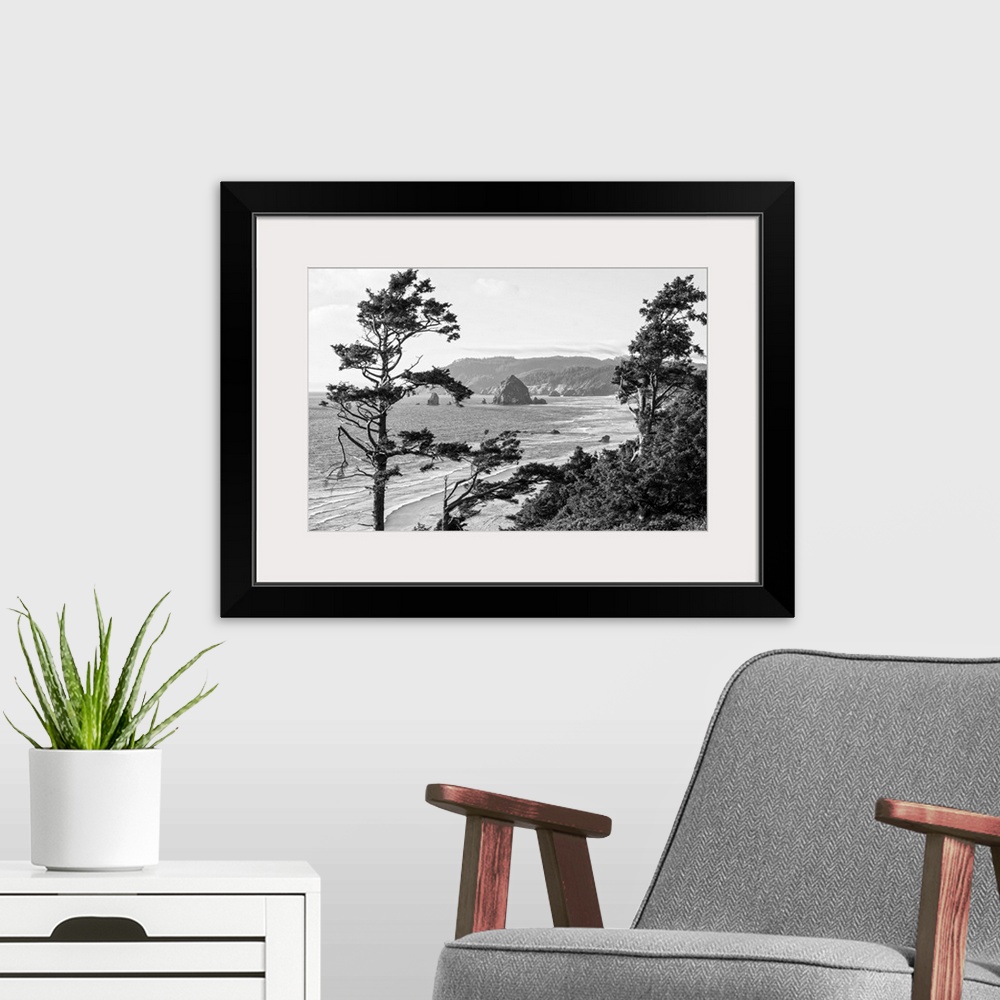 A modern room featuring Black and white landscape photograph of Cannon Beach through the trees with Haystack Rock in the ...