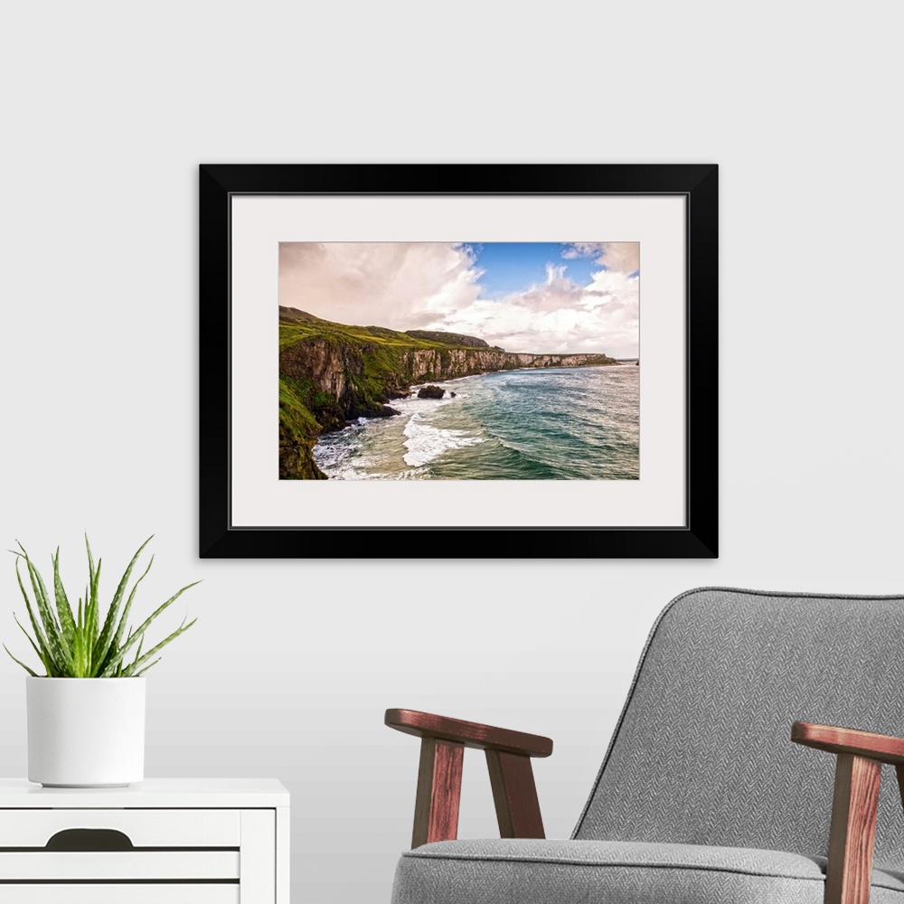 A modern room featuring Landscape photograph of the picturesque Cliffs of Moher with a cloudy sky above, located at the s...