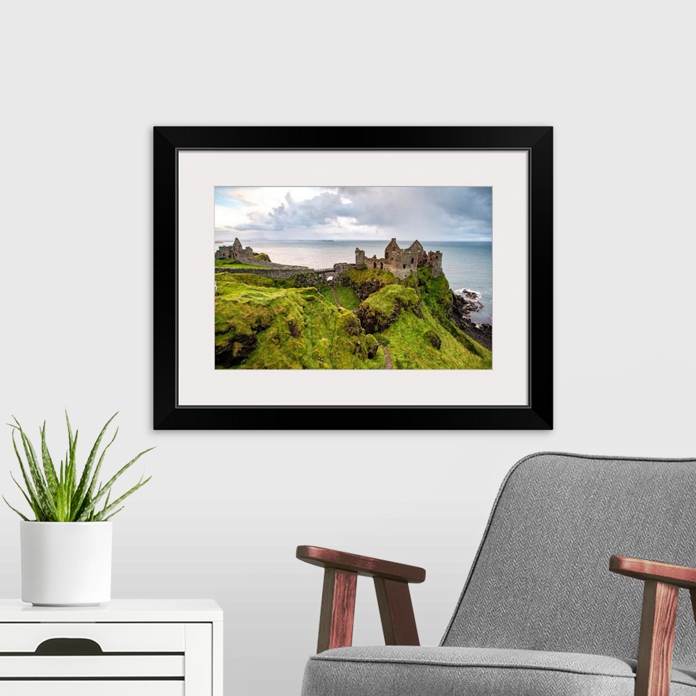 A modern room featuring Landscape photograph of Dunluce Castle next to the ocean, taken from a higher point.