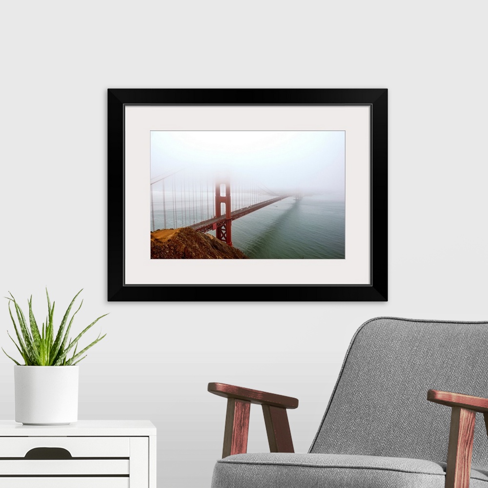 A modern room featuring Landscape photograph of fog taking over the Golden Gate Bridge.