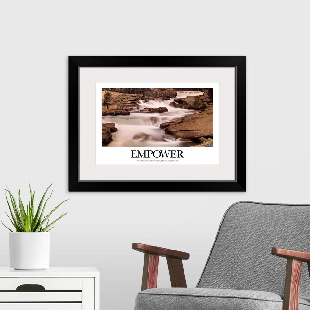 A modern room featuring Motivational poster depicting a stream flowing through rocks with the text, "Empower: Our greates...