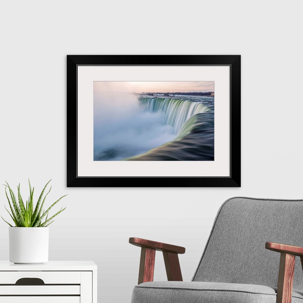 A modern room featuring Water cascades down at Horseshoe Falls while dramatic mist ascents to meet the rising sun.