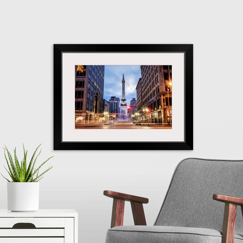 A modern room featuring The Soldiers and Sailors Monument in the evening with lights from passing traffic in Indianapolis...