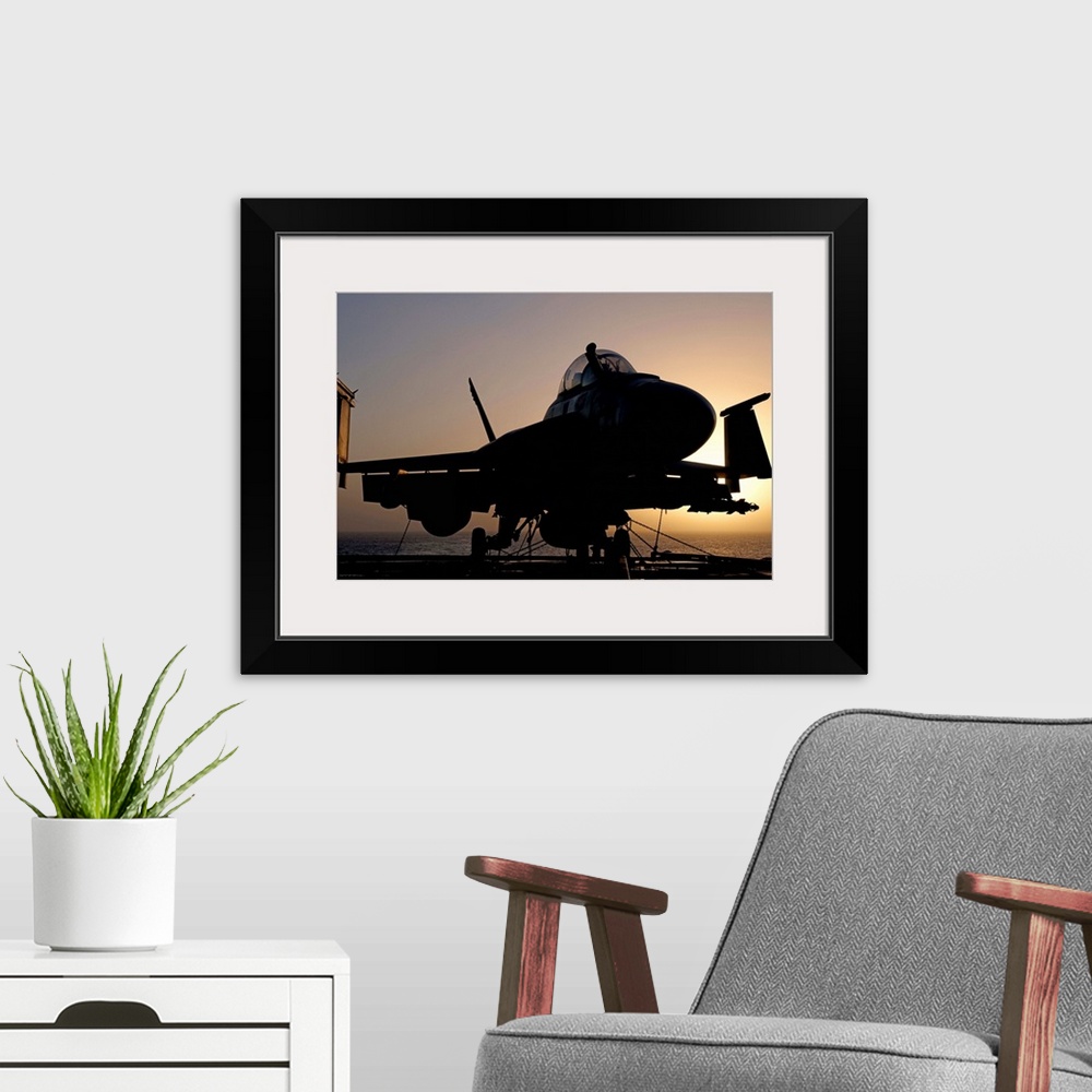 A modern room featuring Silhouette of a US Navy F/A-18E Super Hornet parked on the flight deck of aircraft carrier USS Ni...