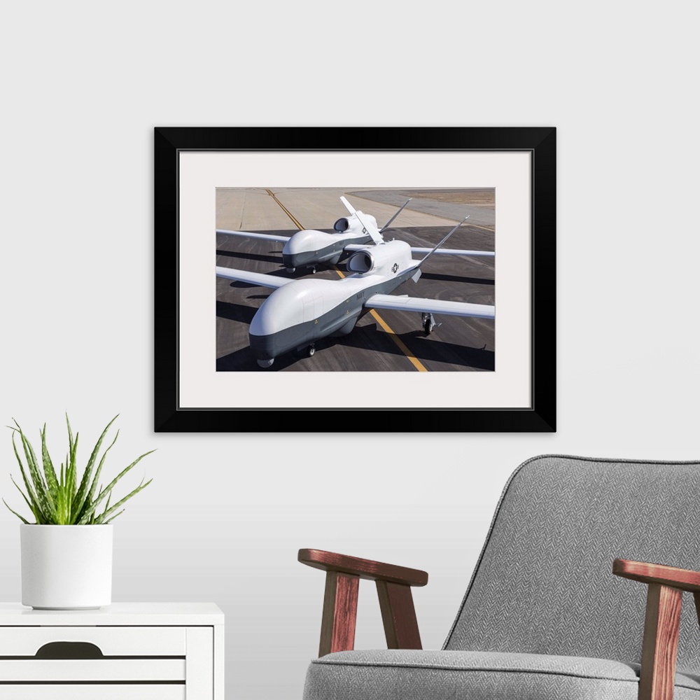 A modern room featuring May 21, 2013 - Two Northrop Grumman MQ-4C Triton unmanned aerial vehicles on the tarmac at a Nort...