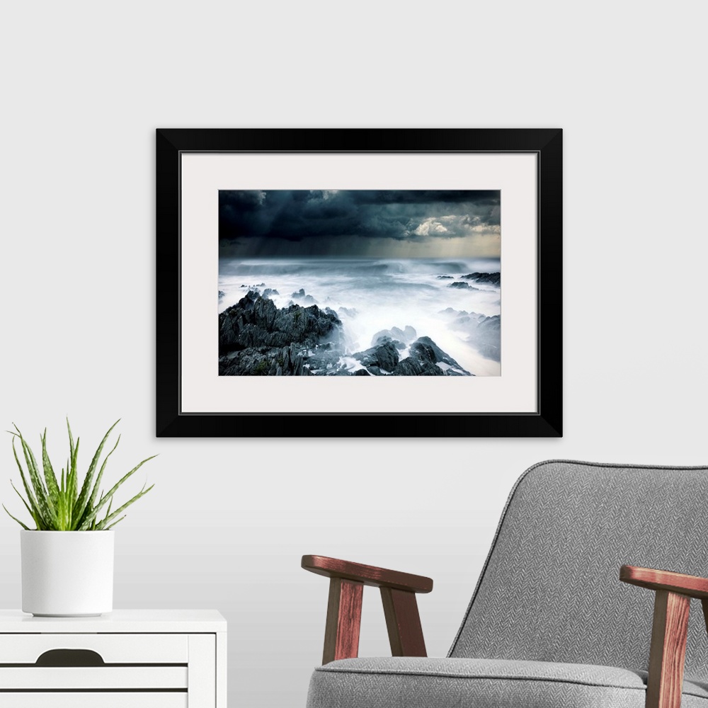 A modern room featuring Stormy seascape with rough surf and dark clouds and rocks