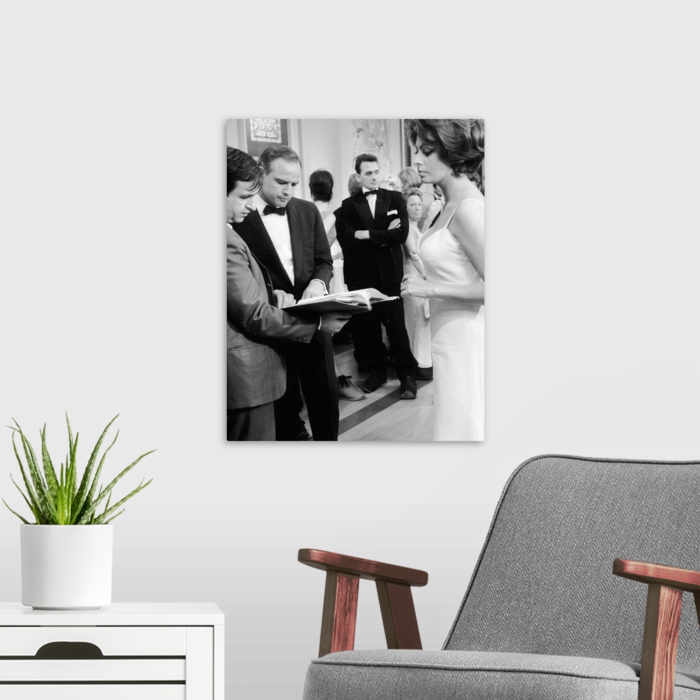 A modern room featuring April 1966:  American film star, Marlon Brando, checks his script whilst Sophia Loren looks on, d...