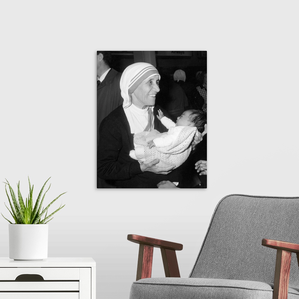 A modern room featuring Christian missionary Mother Teresa of Calcutta (1910 - 1997) holding a baby at Heathrow Airport, ...