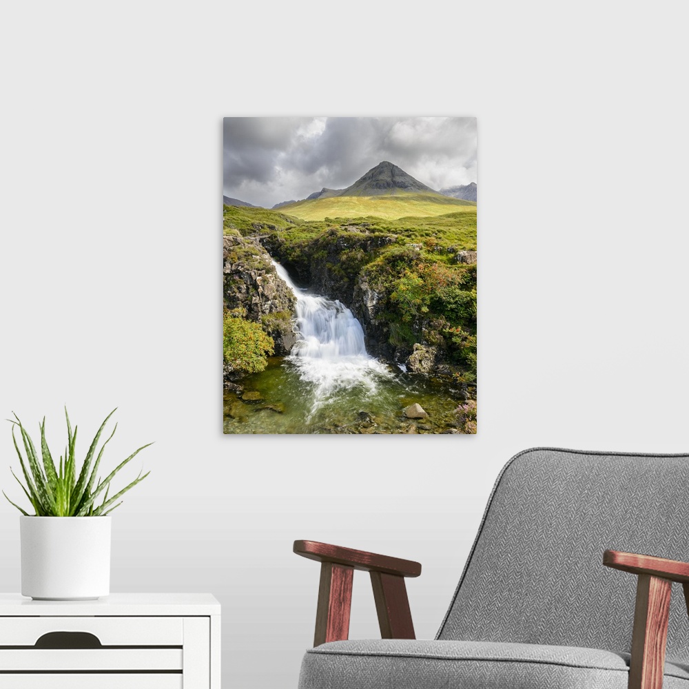 A modern room featuring A photograph of a Scottish landscape with a mountain in the distance and a waterfall in the foreg...