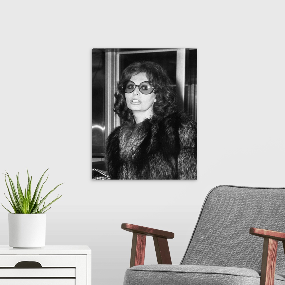 A modern room featuring Sophia Loren in large sunglasses and fur at Rome's airport, May 14, 1974.