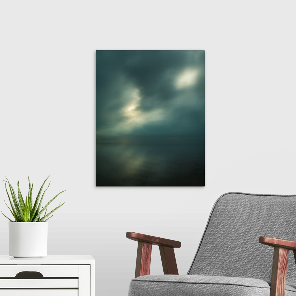A modern room featuring Dream-like photograph of a calm ocean with the sun starting to peak through a cloudy sky.