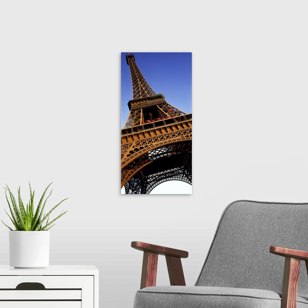 A modern room featuring Vertical, close up, low angle photograph of the Eiffel Tower against a blue sky.
