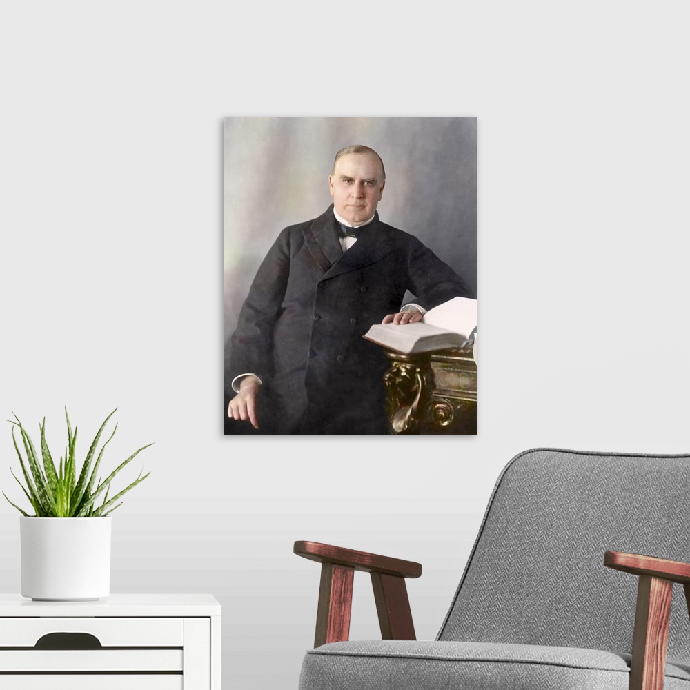 A modern room featuring President William McKinley, half-length portrait, seated at desk, facing front, circa 1900.
