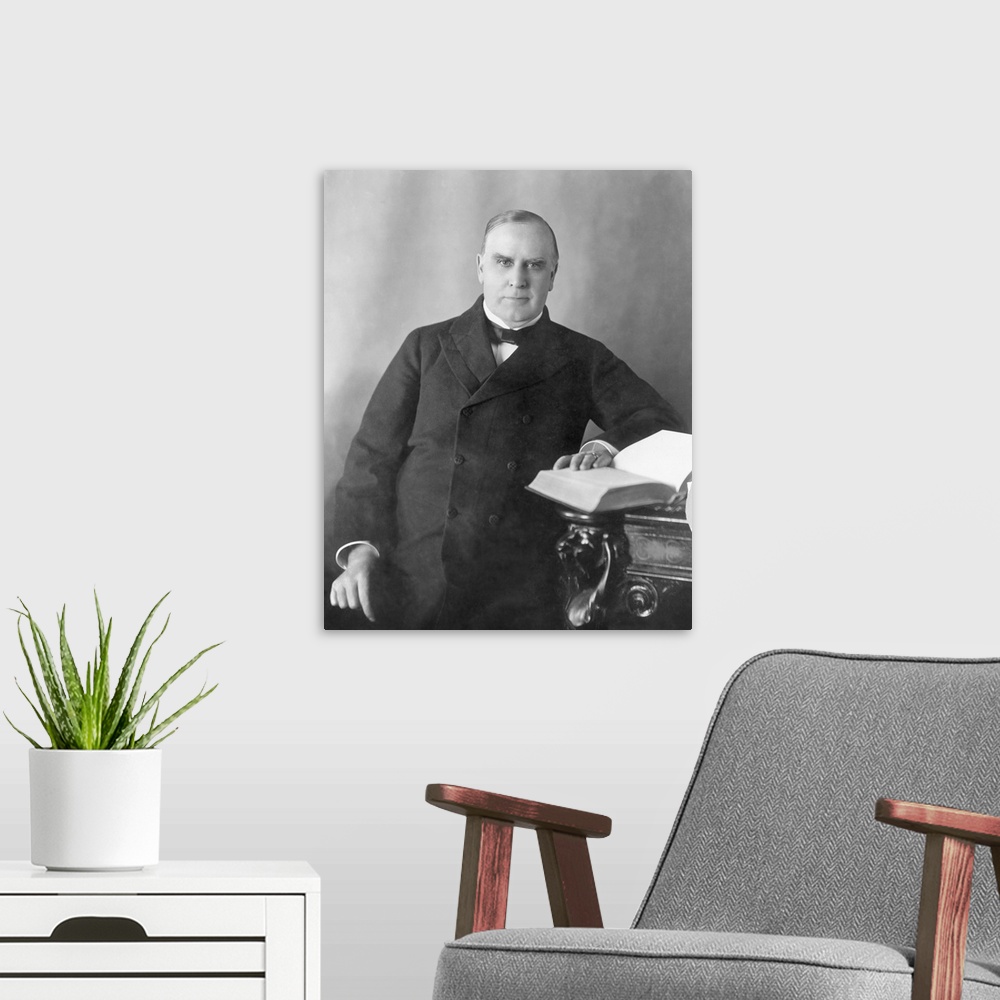 A modern room featuring President William McKinley seated at desk, circa 1900.