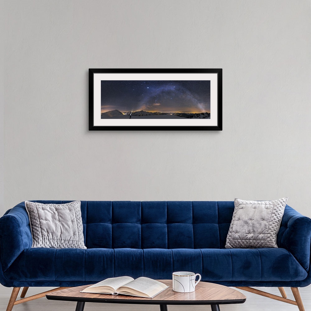 A modern room featuring A panoramic photograph of a person standing in a desolate mountainous snowscape under a starry ni...