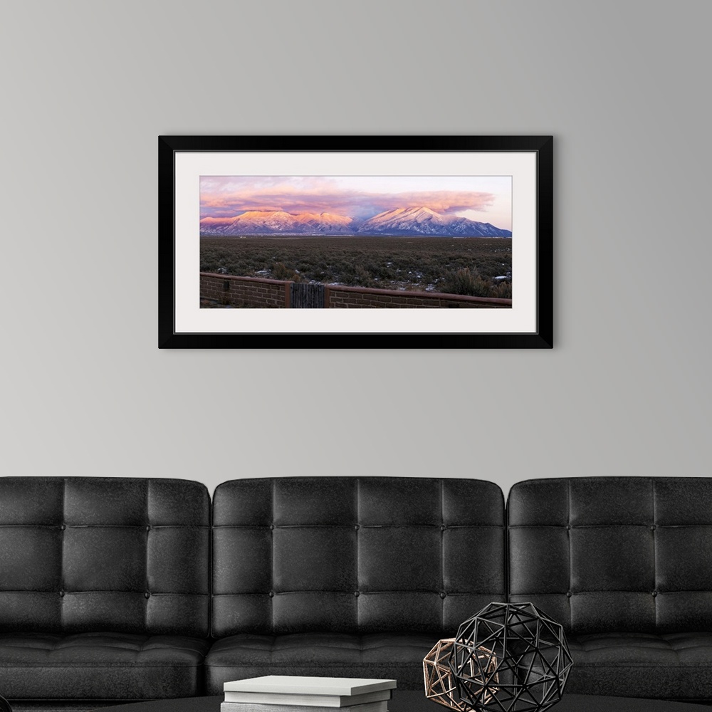 A modern room featuring Mountain range viewed from an adobe brick wall and Sangre De Cristo Mountains, New Mexico, USA.