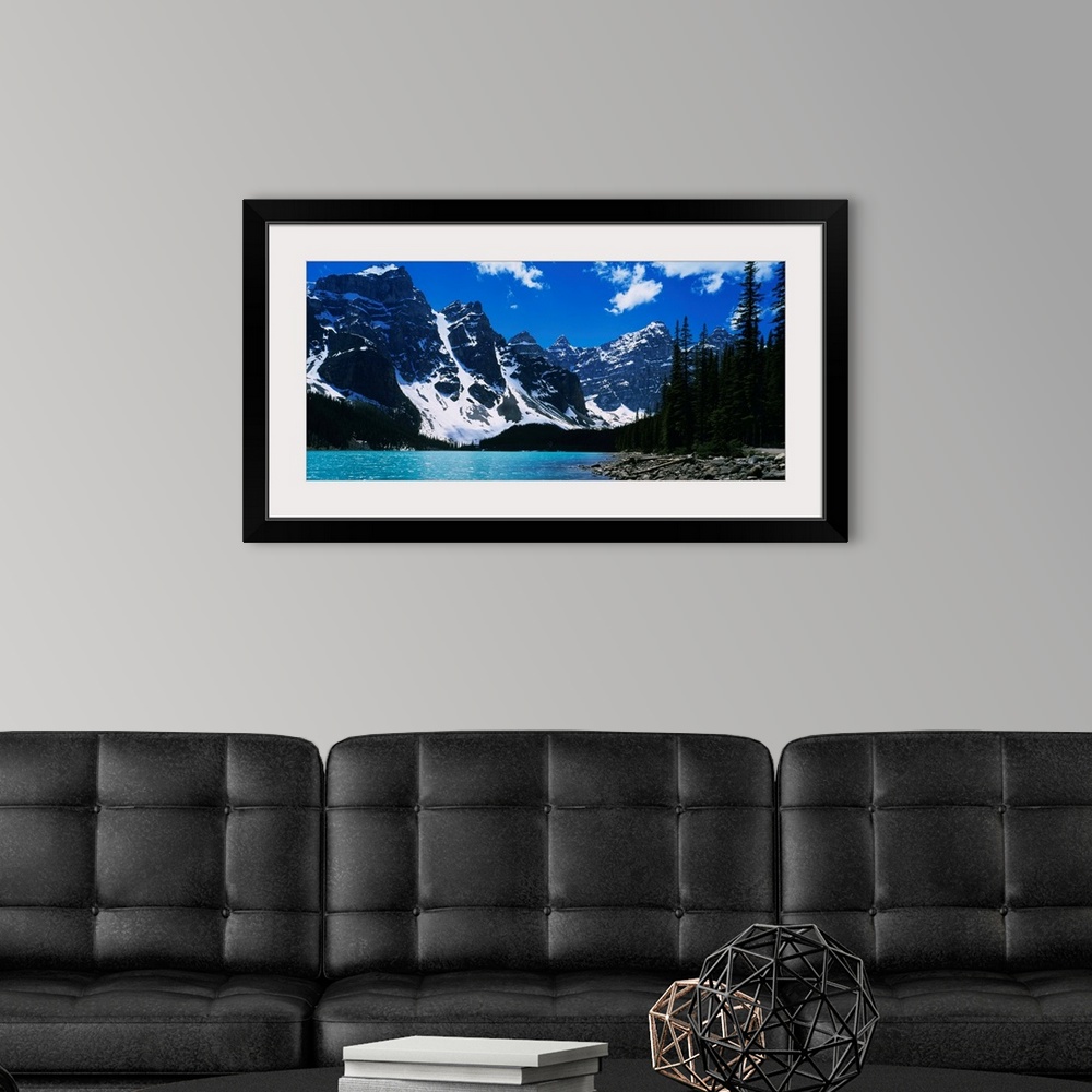 A modern room featuring A landscape photograph of snow covered mountains surround a lake on this horizontal wall art.