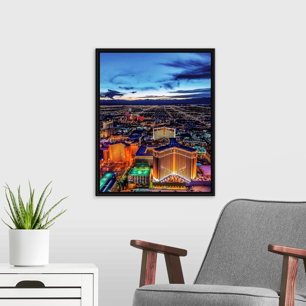 A modern room featuring Aerial view of the Las Vegas Strip illuminated in the early evening with cloudy skies.