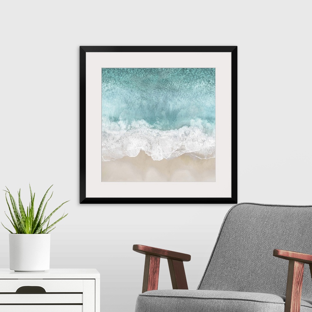 A modern room featuring One artwork in a series of aerial shots of a beach as light blue waves break upon the shore.