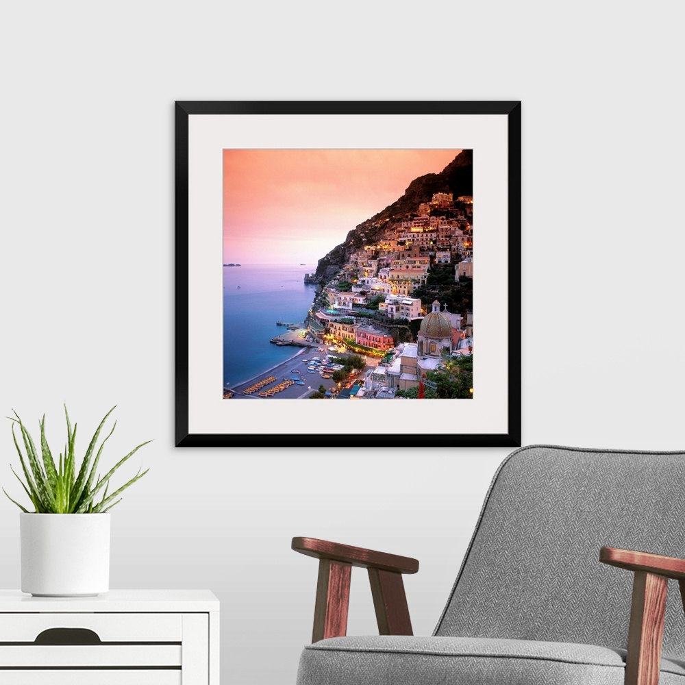 A modern room featuring A square shaped photograph of the charming Italian town of Positano at sunset. Built into the cli...