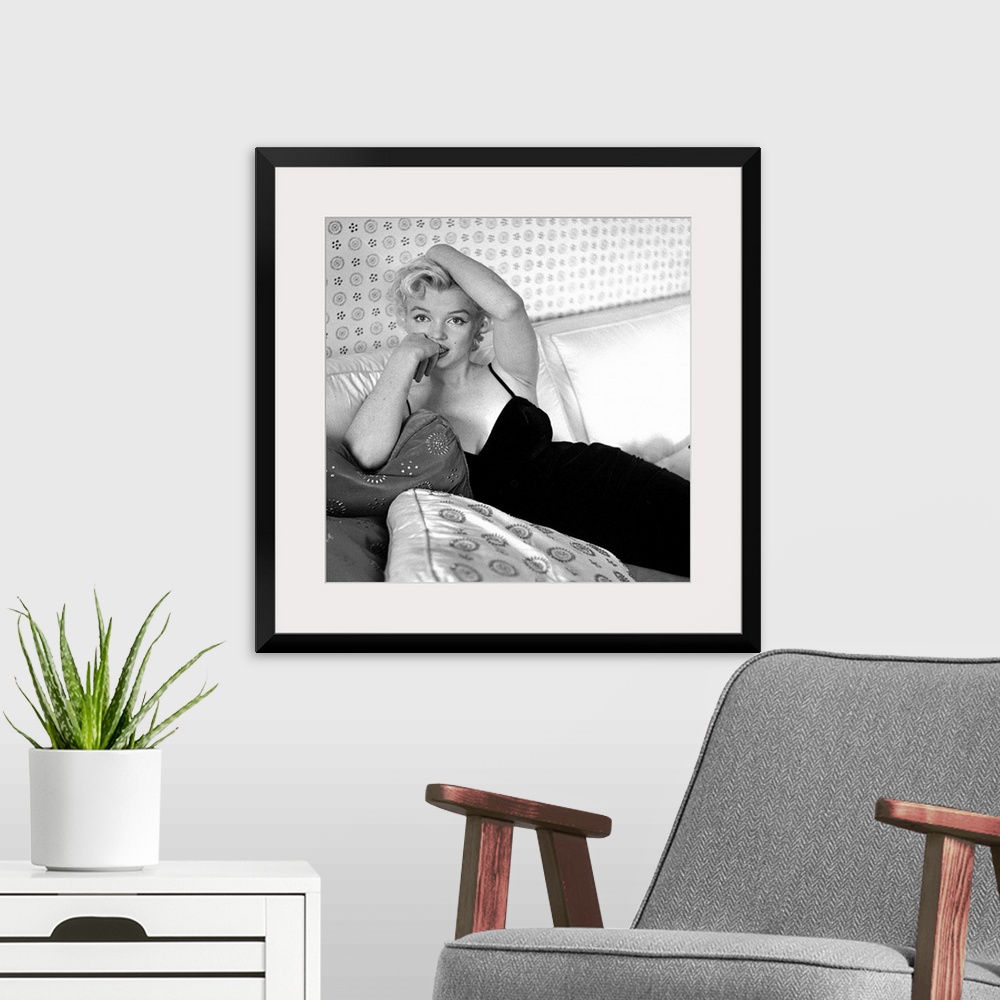 A modern room featuring Wall art of Marilyn Monroe sitting on a sofa looking at the camera.
