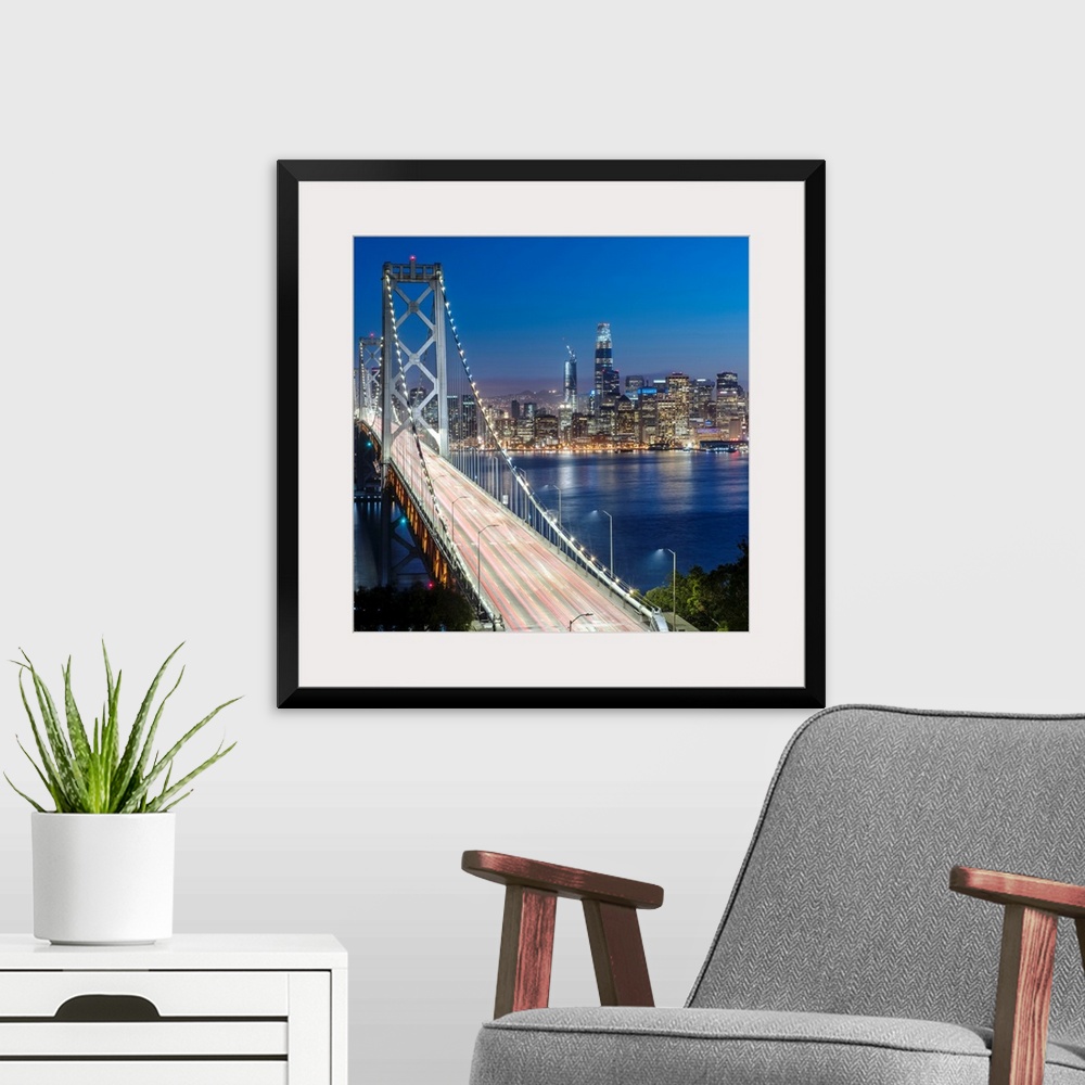 A modern room featuring Square photograph of the Bay Bridge at dusk with downtown San Francisco lit up in the background.
