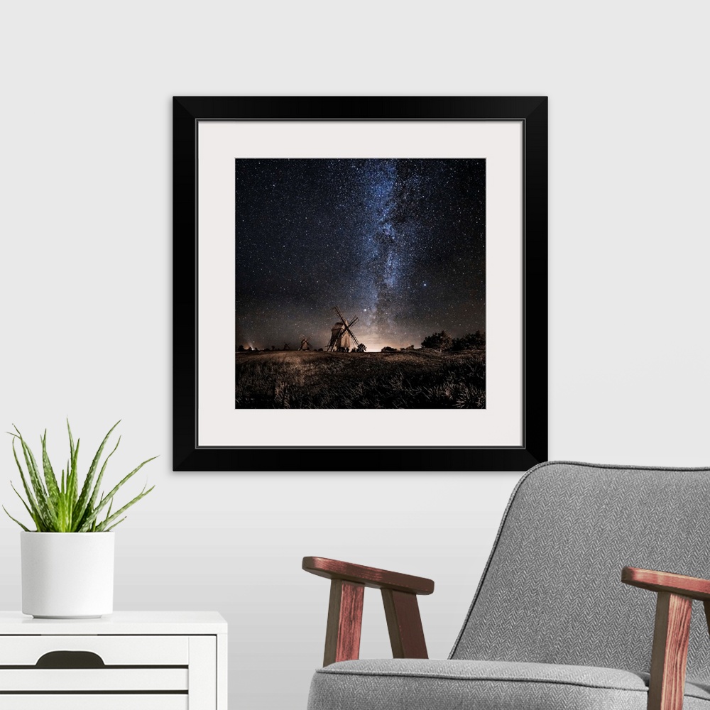 A modern room featuring A dramatic photograph of a countryside scene with windmills in the distance and a starry night sk...