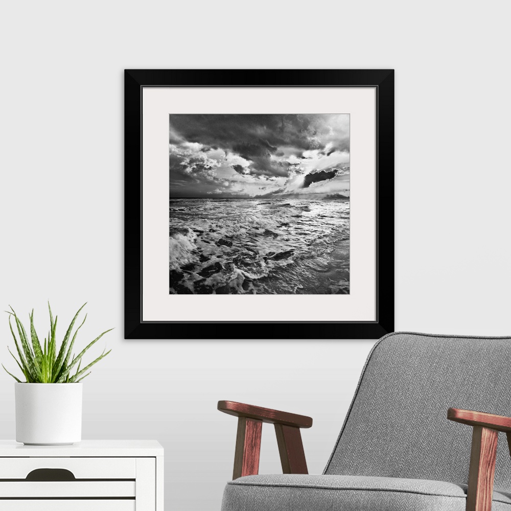 A modern room featuring A black and white image of the sea with crashing waves on the beach.