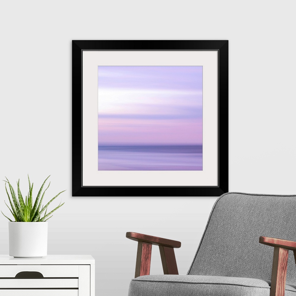 A modern room featuring Abstract artwork of a sunset sky over the ocean with a haze over the entire piece to give it a so...
