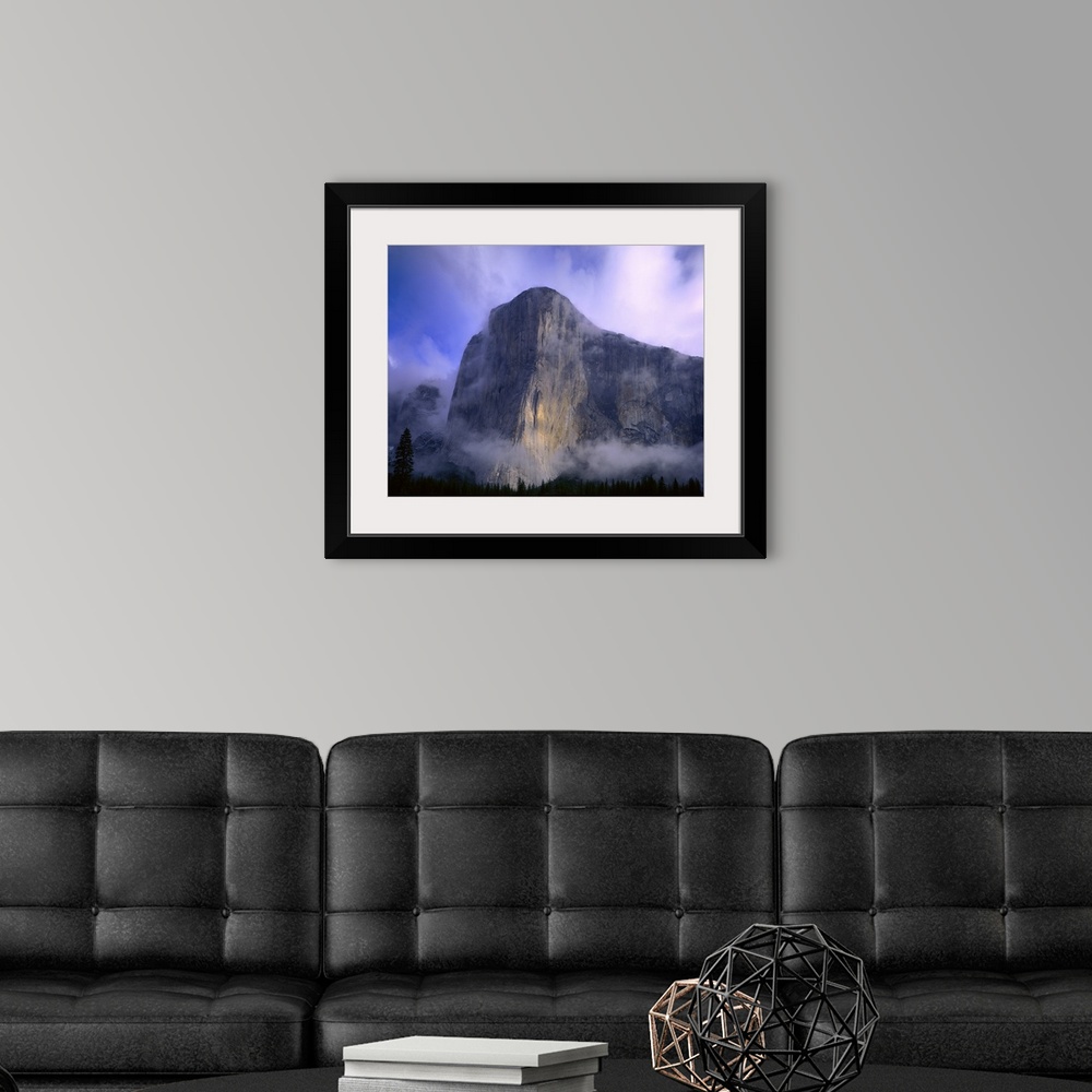 A modern room featuring Large photo on canvas of a mountain in Yosemite bathed in fog with a dense forest below it.
