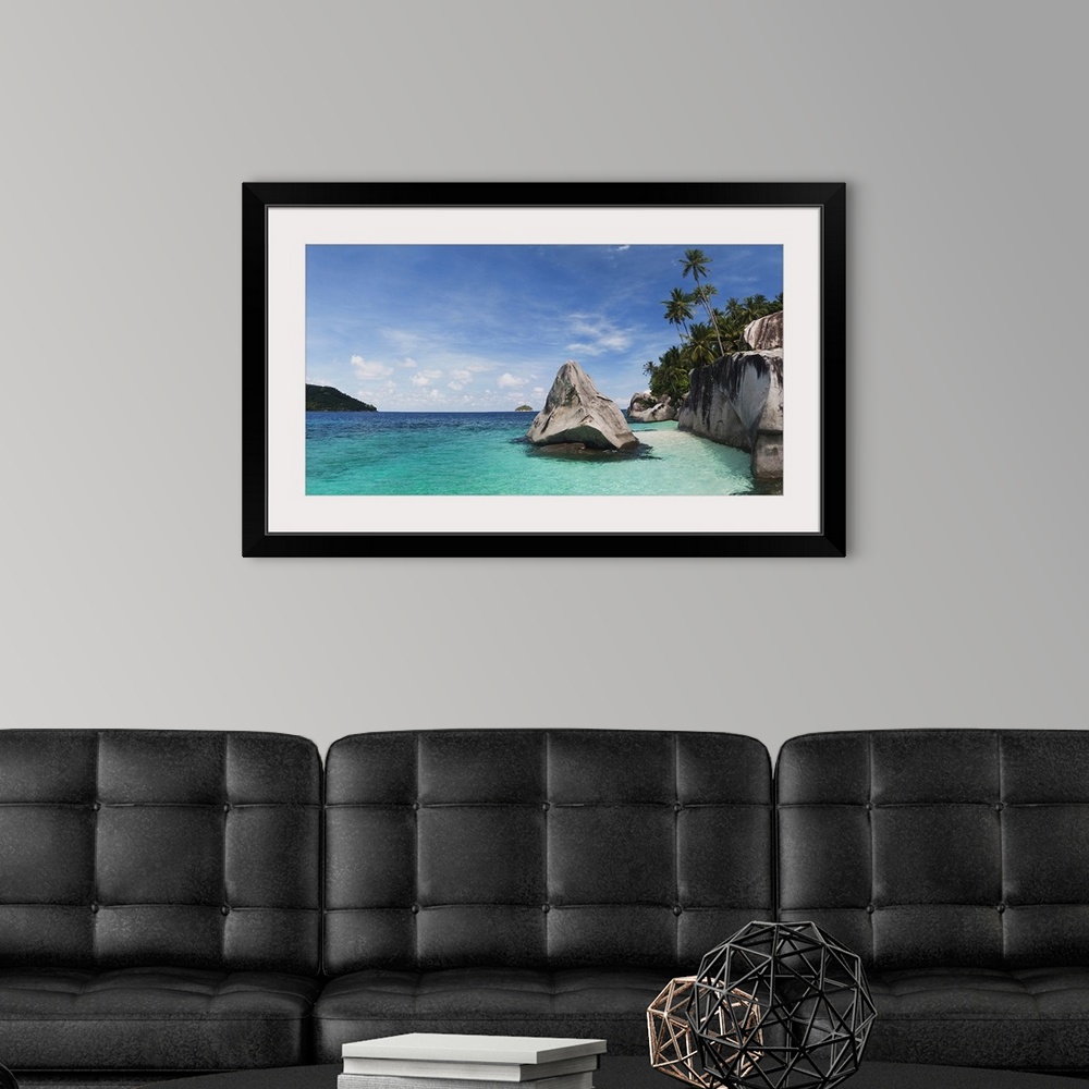 A modern room featuring Landscape photograph on a large canvas of clear blue waters in Malaysia, along the rocky shorelin...