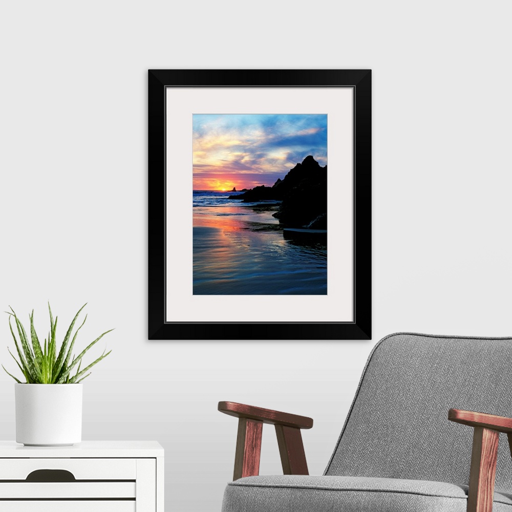 A modern room featuring Sun below the horizon in a seascape with a rocky beach and waves.