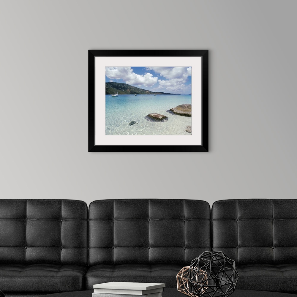 A modern room featuring Big photo print of boats floating near the shore of a clear ocean with hills in the background.