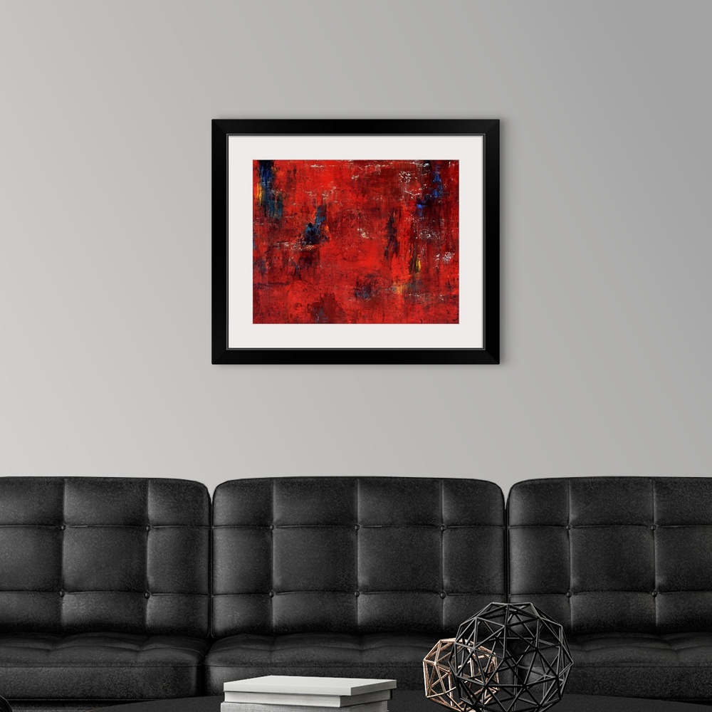 A modern room featuring Abstract painting featuring shades of red and maroon with swipes of blue and yellow.