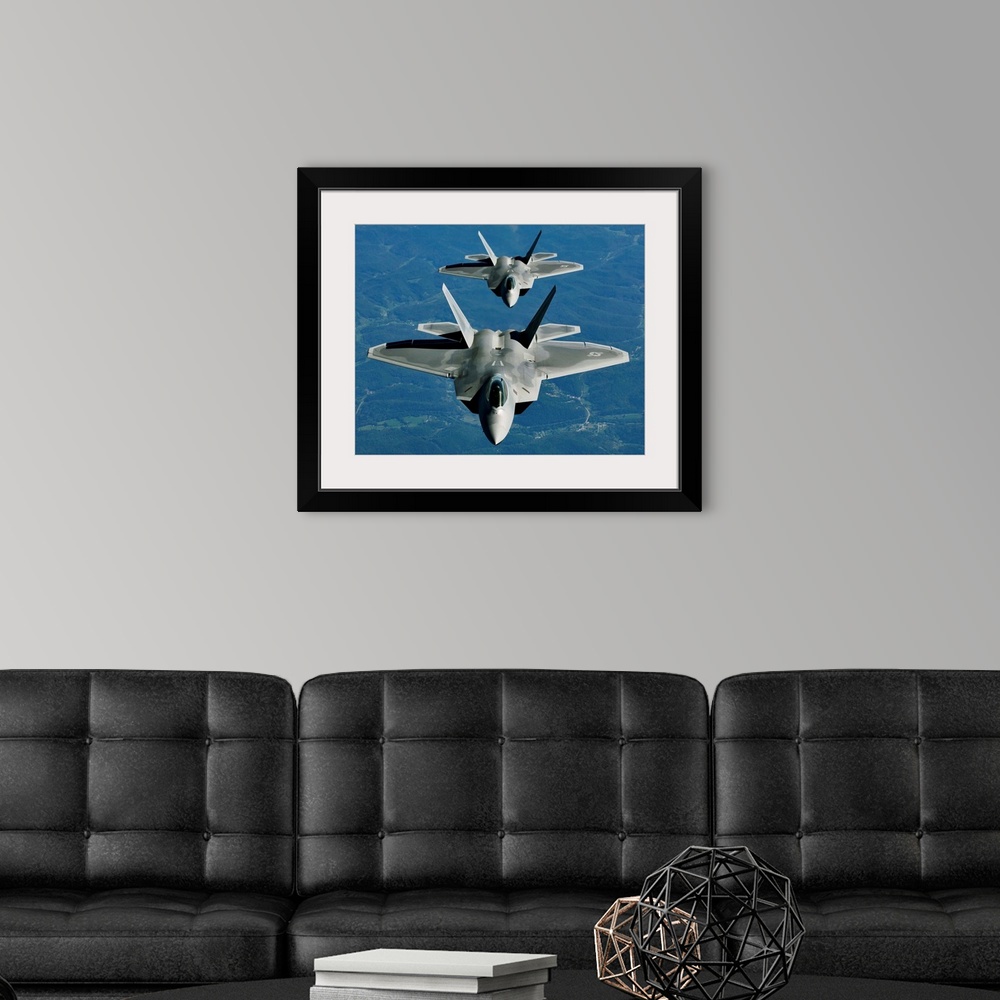 A modern room featuring Two F-15's fly in formation behind a KC-10 Extender.