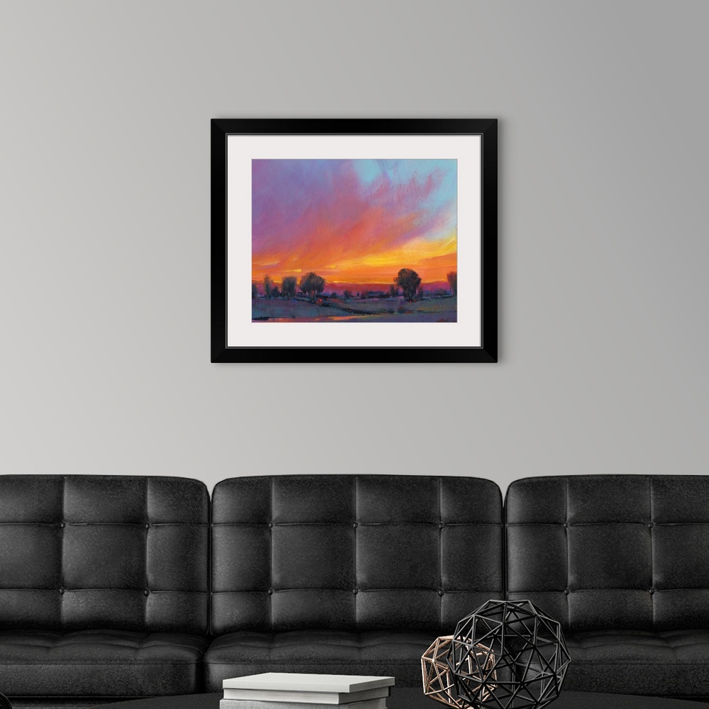 A modern room featuring Contemporary painting with vibrant oranges and yellows of a sun setting over the countryside.