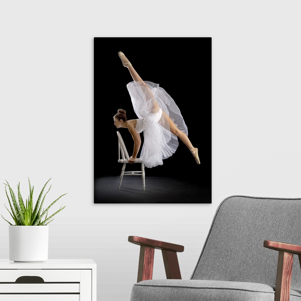A modern room featuring A ballerina posing on a chair with one leg high in the air.