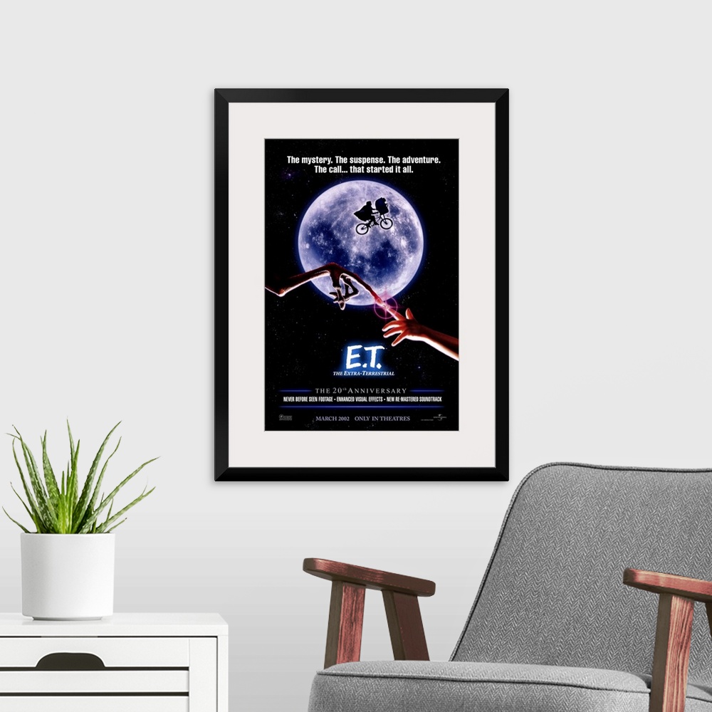 A modern room featuring A large vertical print of the 20th anniversary poster of E.T. It depicts the famous scene of the ...