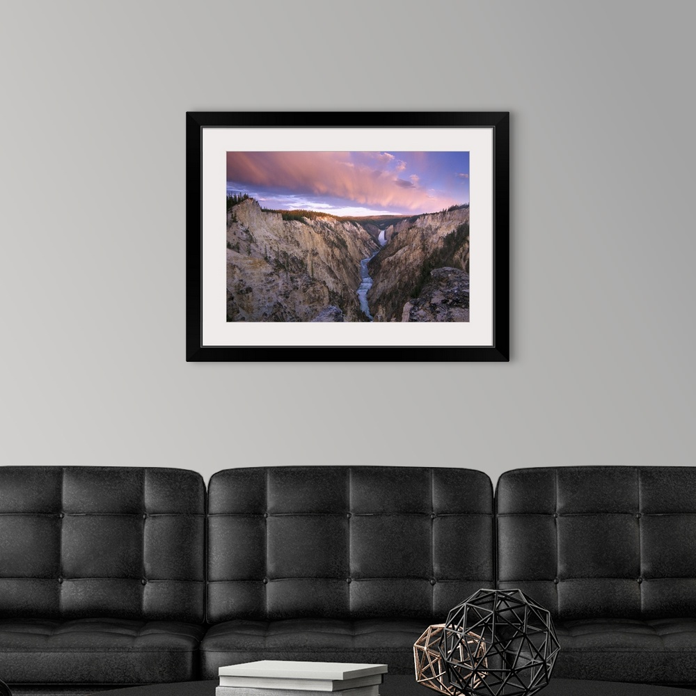 A modern room featuring Lower Yellowstone Falls running through a valley in Yellowstone National Park with the sunset hit...