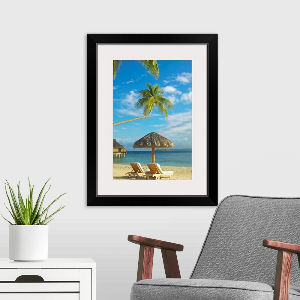 A modern room featuring Photograph taken of two beach chairs and an umbrella sitting on a beach in Tahiti. A palm tree st...