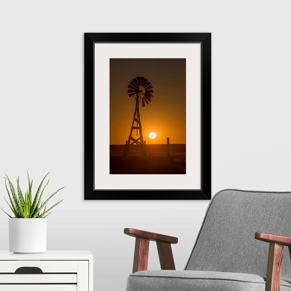 A modern room featuring Silhouette photograph of a windmill at sunset with the round sun sitting right above the horizon ...