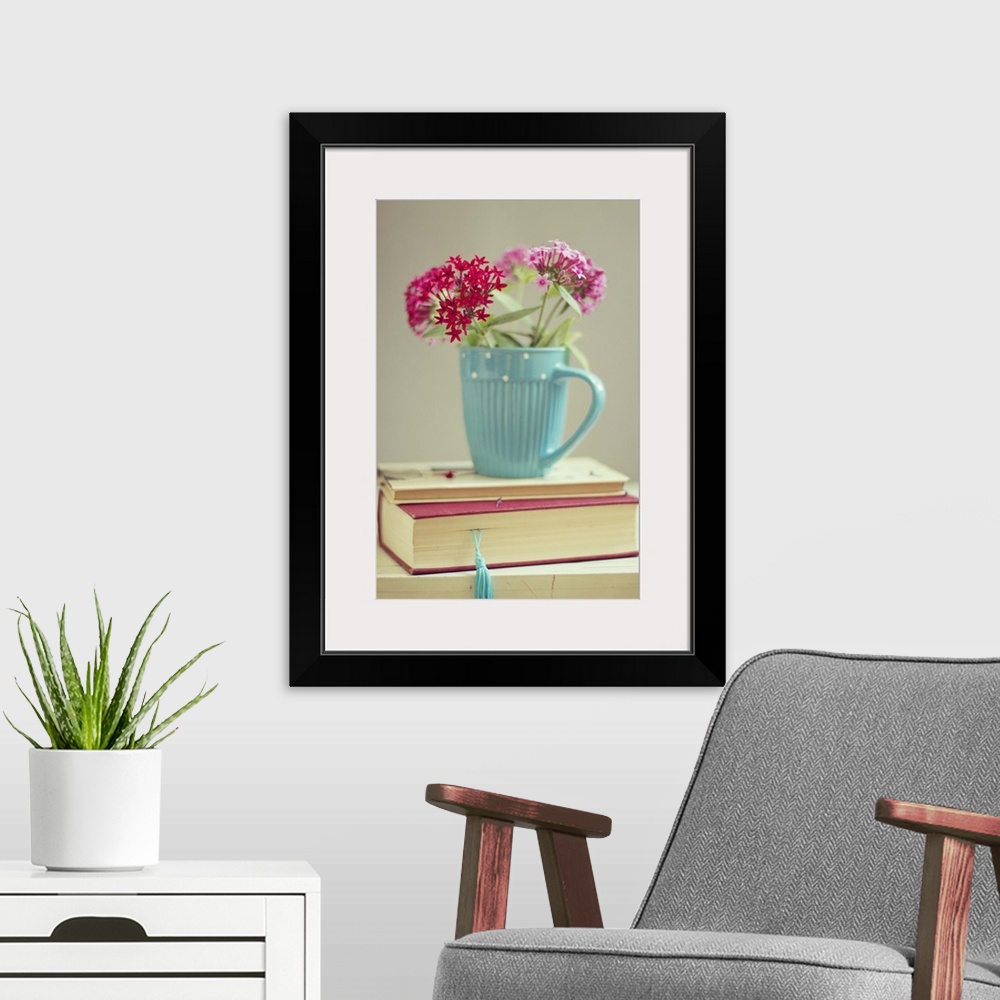 A modern room featuring Flowers in blue cup on two books.