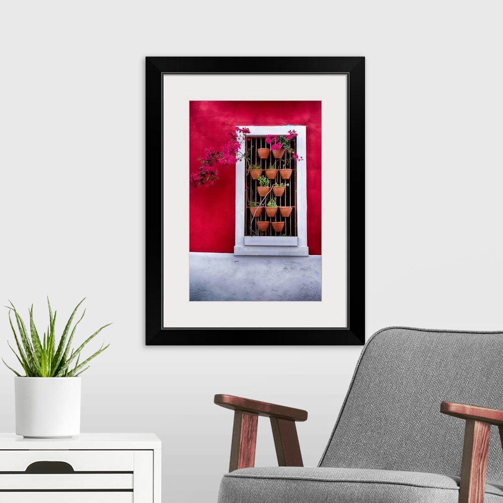 A modern room featuring Fine art photo of a window in a red wall with several potted plants.