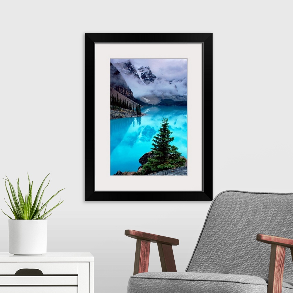 A modern room featuring From the National Geographic Collection a photograph of mountains reflecting in water as clouds p...