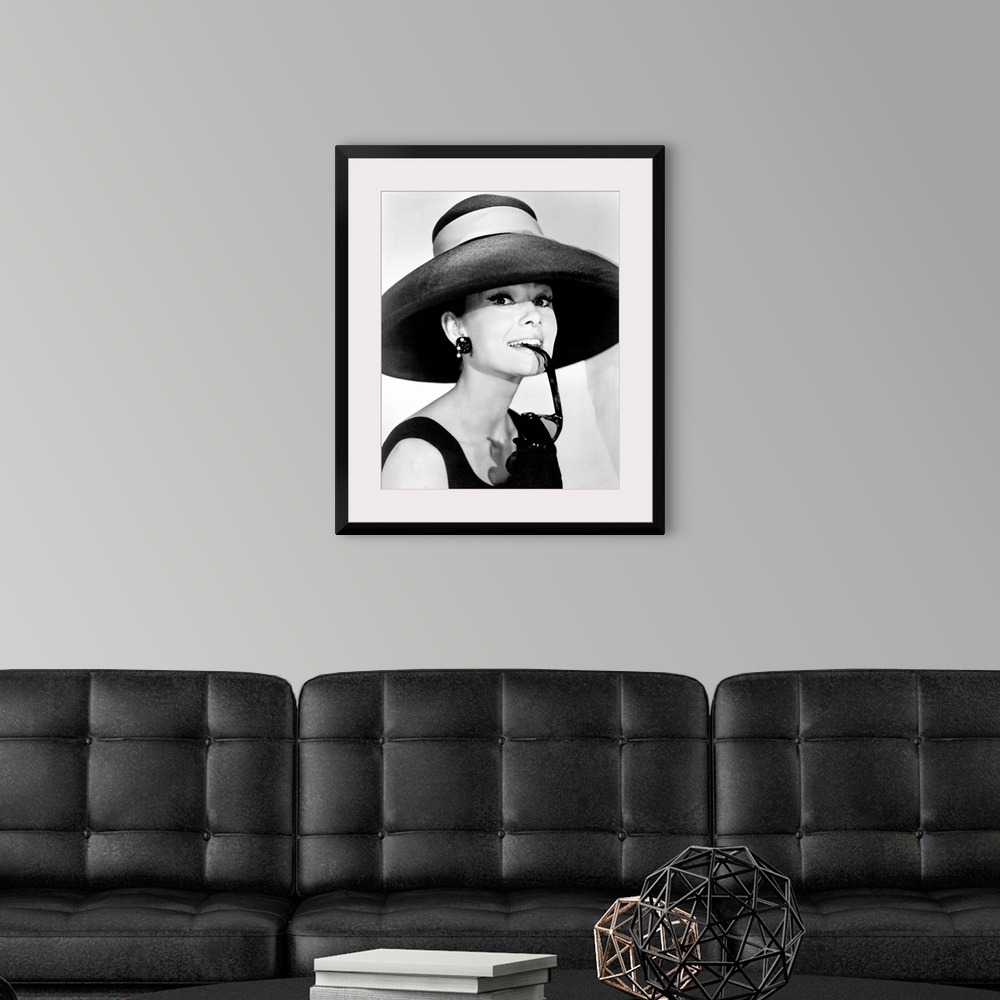 A modern room featuring Large photograph of Audrey Hepburn in a giant sun hat holding sunglasses in her mouth as she glan...